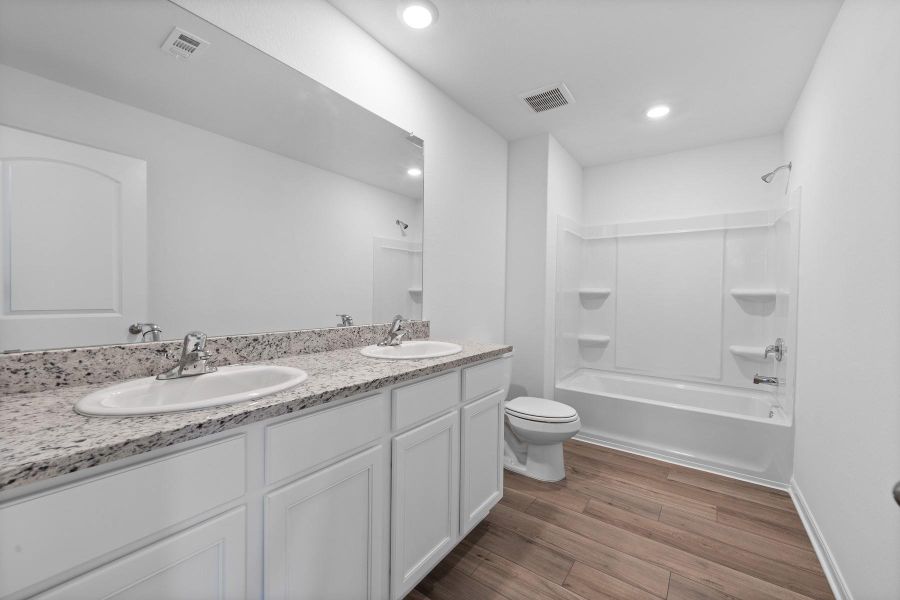 Full bath with double vanity, dark wood-style floors, tub / shower combination, and recessed lighting