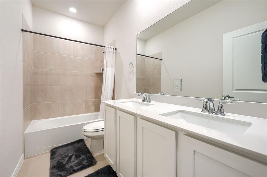Bathroom featuring shower / bath combo with shower curtain, double vanity, and light tile patterned flooring Bathroom featuring shower / bath combo with shower curtain, double vanity, and light tile patterned flooring