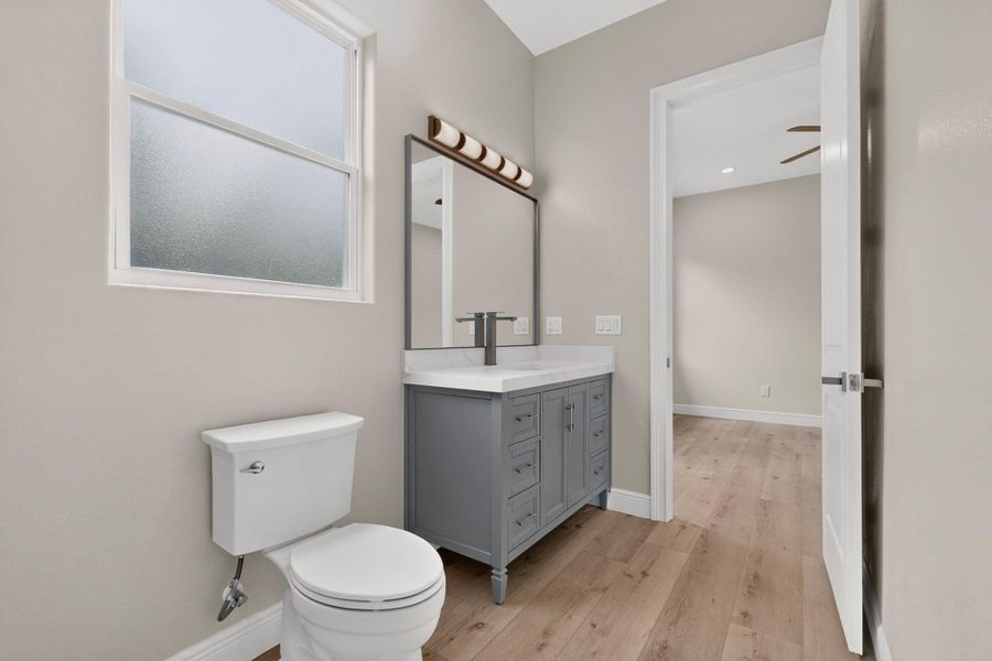 Plank flooring and a contemporary vanity highlight this sleek bathroom space.