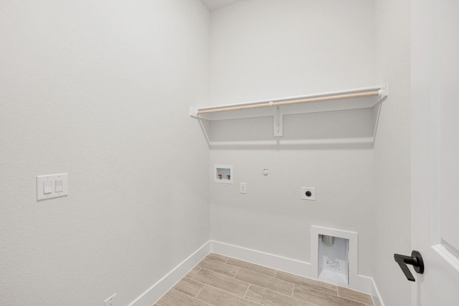 Laundry room with white walls, built-in shelf, washer and dryer hookups, and tile floor