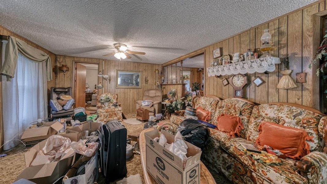 Miscellaneous room with a textured ceiling, ceiling fan, and wood walls