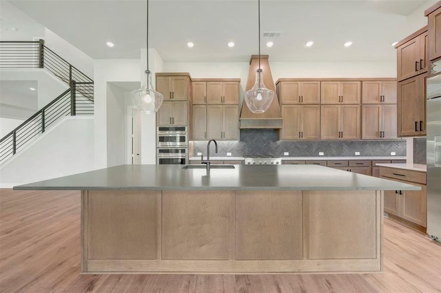 Kitchen with a large island, pendant lighting, and light wood-style floors