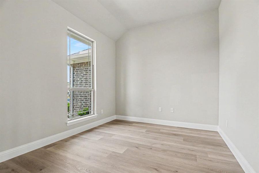 Bright room featuring a single-pane window, vaulted ceiling, and wood-finish flooring Bright room featuring a single-pane window, vaulted ceiling, and wood-finish flooring