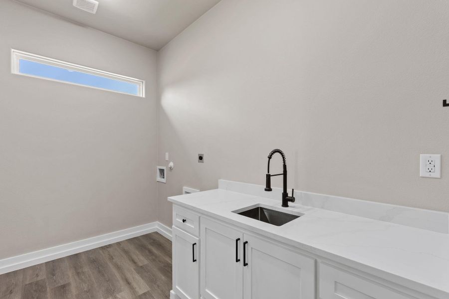 A well-appointed laundry area offers practical convenience with a functional sink and ample counter space. A well-appointed laundry area offers practical convenience with a functional sink and ample counter space.