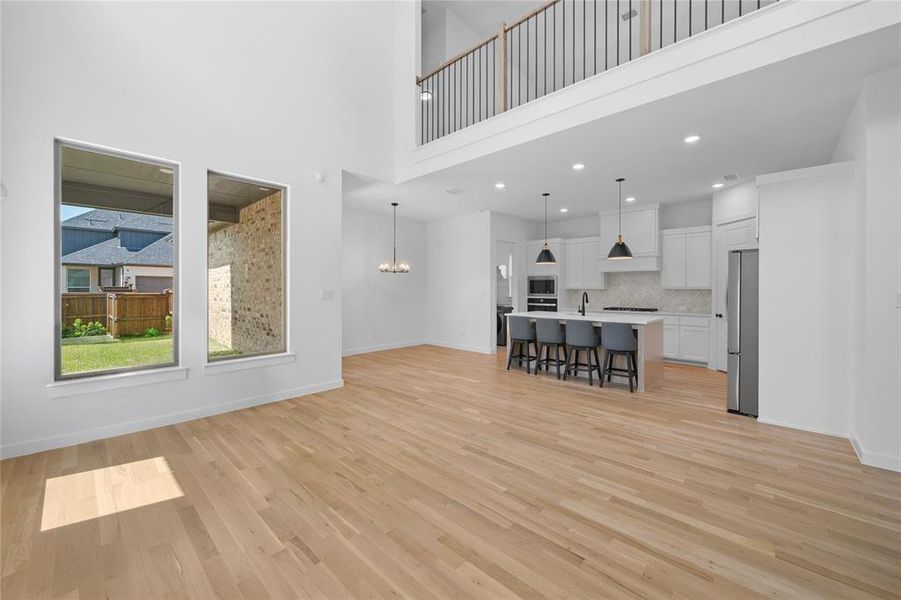 Expansive open-concept interior featuring light wood-finish flooring and a two-story ceiling