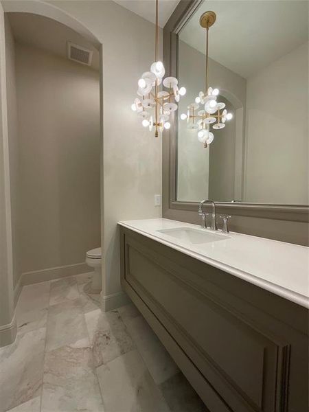 Bathroom with visible vents, an inviting chandelier, marble finish floor, vanity, and toilet