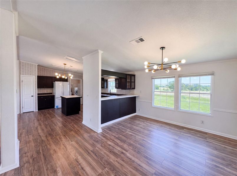 Gleaming wood floors run through an open layout connecting a dining space and kitchen.