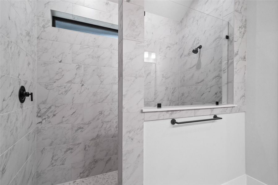The spa-like primary bathroom boasts an oversized walk-in shower wrapped in timeless marble-look tile from floor to ceiling. The spa-like primary bathroom boasts an oversized walk-in shower wrapped in timeless marble-look tile from floor to ceiling.