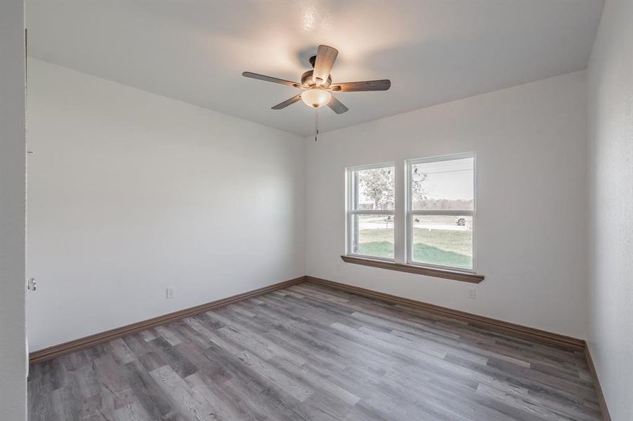 Unfurnished room featuring a ceiling fan, baseboards, and wood finished floors