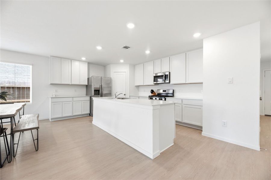 Light and bright kitchen features white cabinetry and stainless steel appliances.