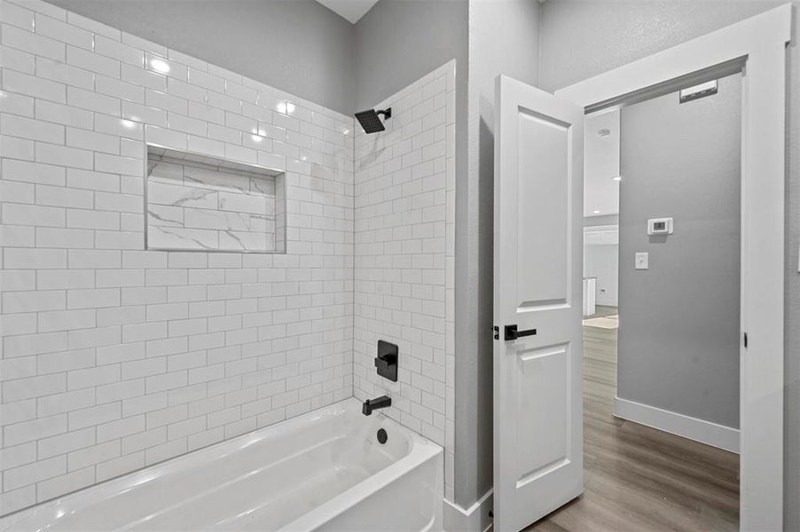 Bathroom with wood-type flooring and tiled shower / bath combo