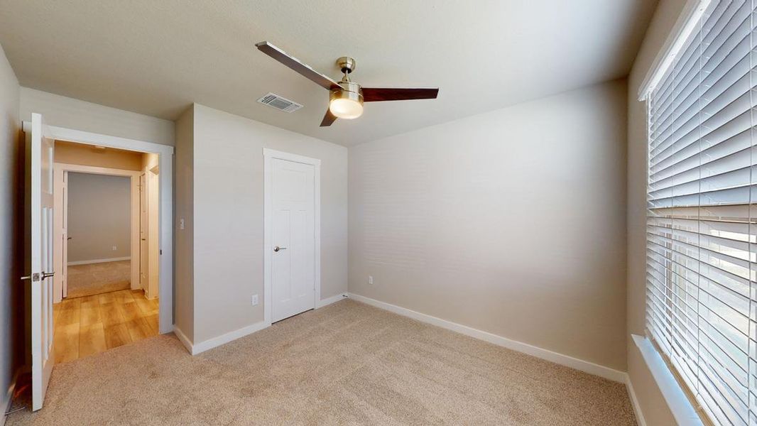 Unfurnished bedroom with light carpet and ceiling fan