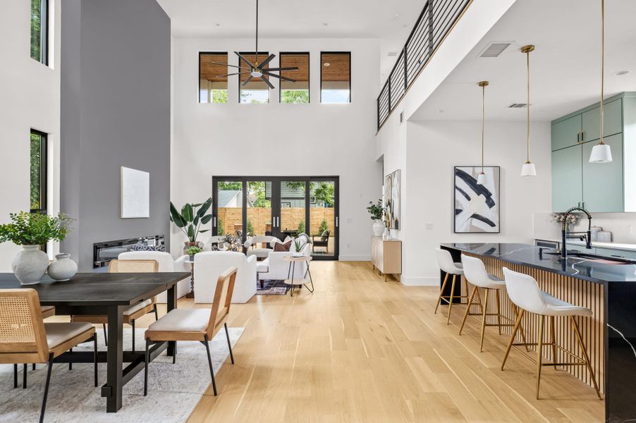 A spacious, airy interior features high ceilings and polished hardwood flooring, connecting dining, living, and kitchen areas. A spacious, airy interior features high ceilings and polished hardwood flooring, connecting dining, living, and kitchen areas.