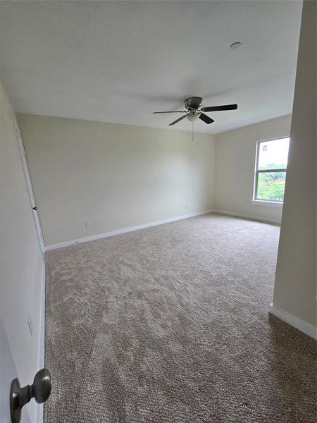 Carpeted empty room featuring baseboards and ceiling fan