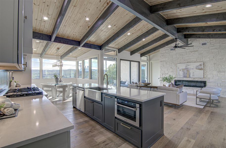 Kitchen with a sink, appliances with stainless steel finishes, wood finished floors, a stone fireplace, and ceiling fan Kitchen with a sink, appliances with stainless steel finishes, wood finished floors, a stone fireplace, and ceiling fan