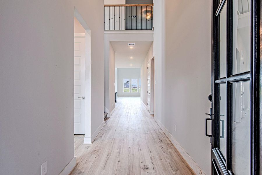 Step into a bright and airy foyer with soaring ceilings, warm-toned floors, and a straight sightline to the light-filled living room beyond. Step into a bright and airy foyer with soaring ceilings, warm-toned floors, and a straight sightline to the light-filled living room beyond.