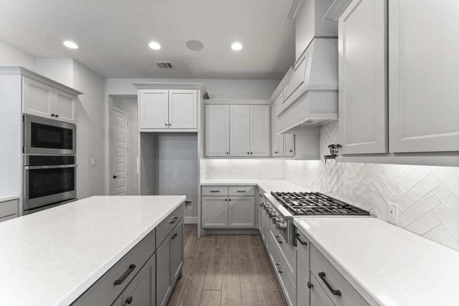 The chef’s kitchen is a true showpiece with GE Café appliances, quartz countertops, double ovens, pot filler, butler’s pantry, soft close drawers, spice racks, and under cabinet lighting. The chef’s kitchen is a true showpiece with GE Café appliances, quartz countertops, double ovens, pot filler, butler’s pantry, soft close drawers, spice racks, and under cabinet lighting.