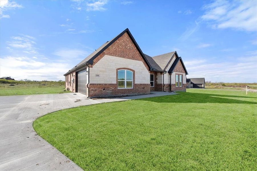 View of side of home featuring a lawn and a garage