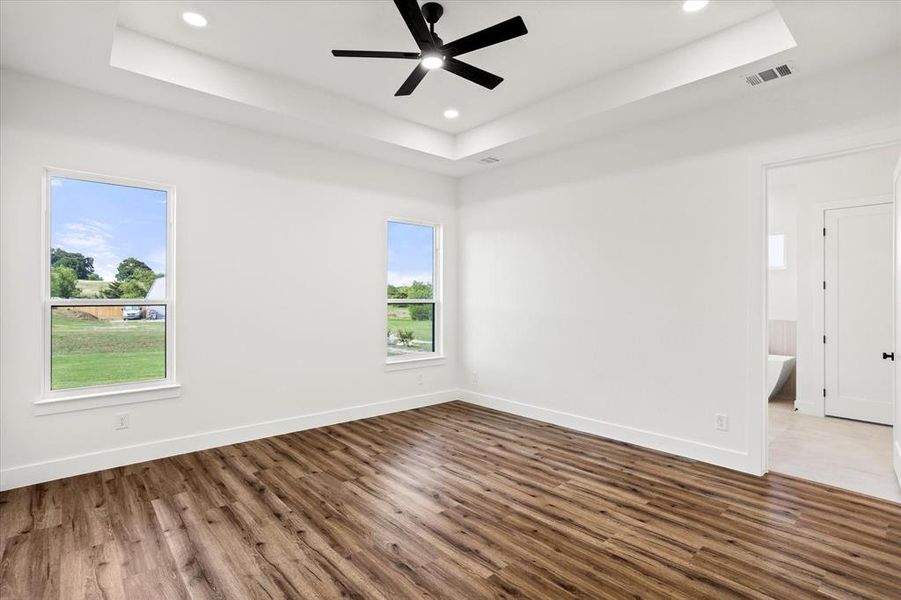 Empty room featuring a raised ceiling, dark wood-style flooring, ceiling fan, and recessed lighting Empty room featuring a raised ceiling, dark wood-style flooring, ceiling fan, and recessed lighting