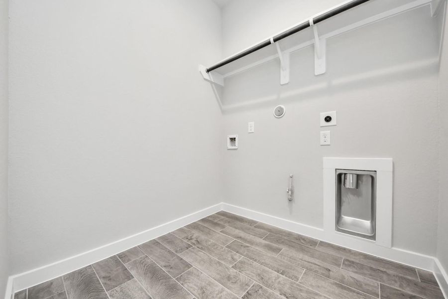 A perfect blend of functionality and comfort. Capture the essence of easy living with a first-floor laundry room, thoughtfully equipped with shelving for effortless organization. Both electric and gas connections available. Sample photo of completed home with similar floor plan. Actual colors and selections may vary.