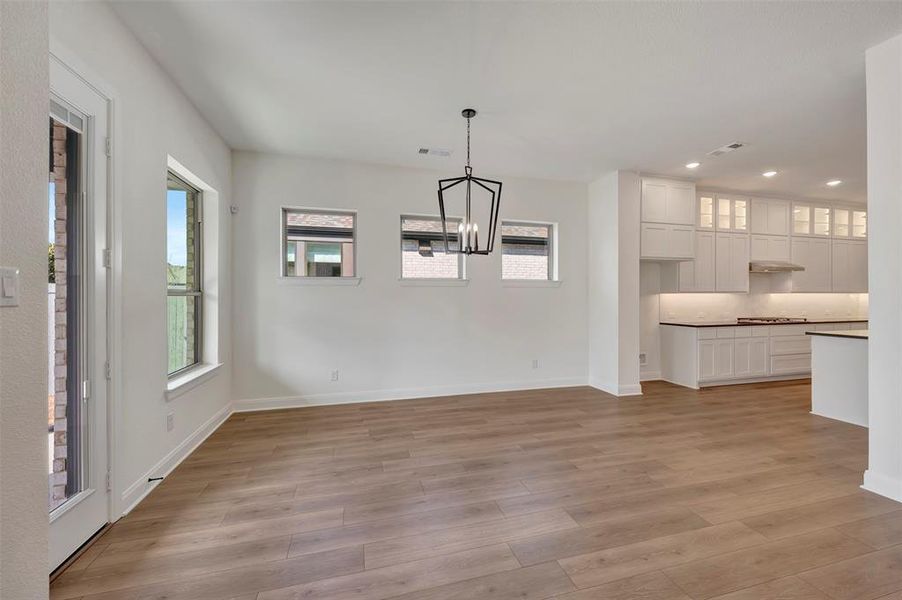 Unfurnished dining area featuring light wood-type flooring and suspended lighting