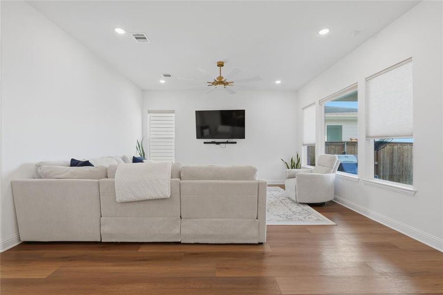 Living area featuring wood-finish flooring, recessed lighting, and a ceiling fan with brass accents Living area featuring wood-finish flooring, recessed lighting, and a ceiling fan with brass accents