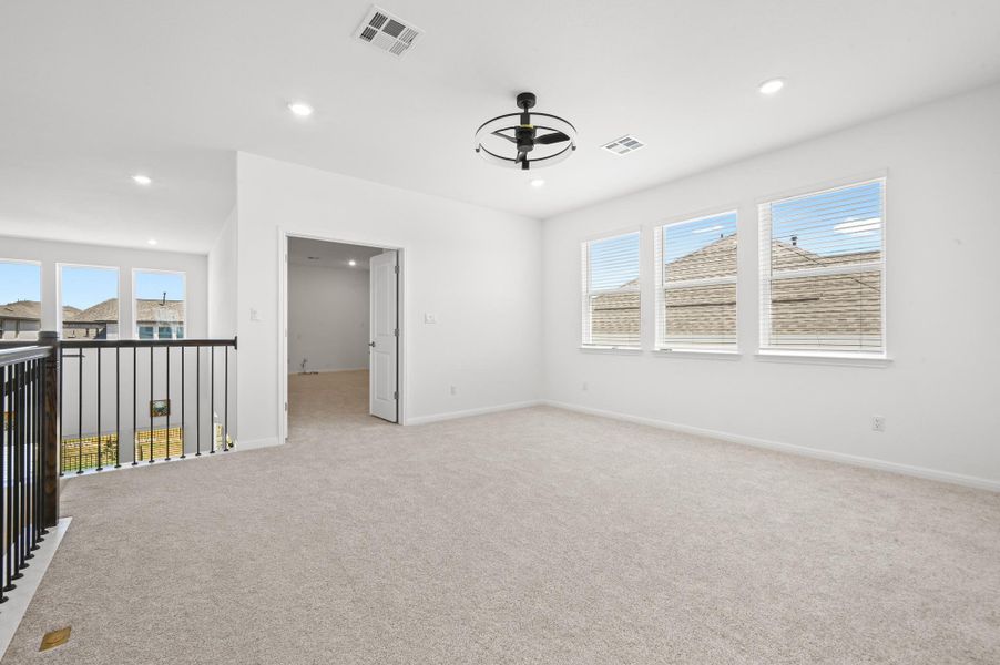 Plentiful natural light streams across a spacious upper-level loft complete with neutral carpeting.