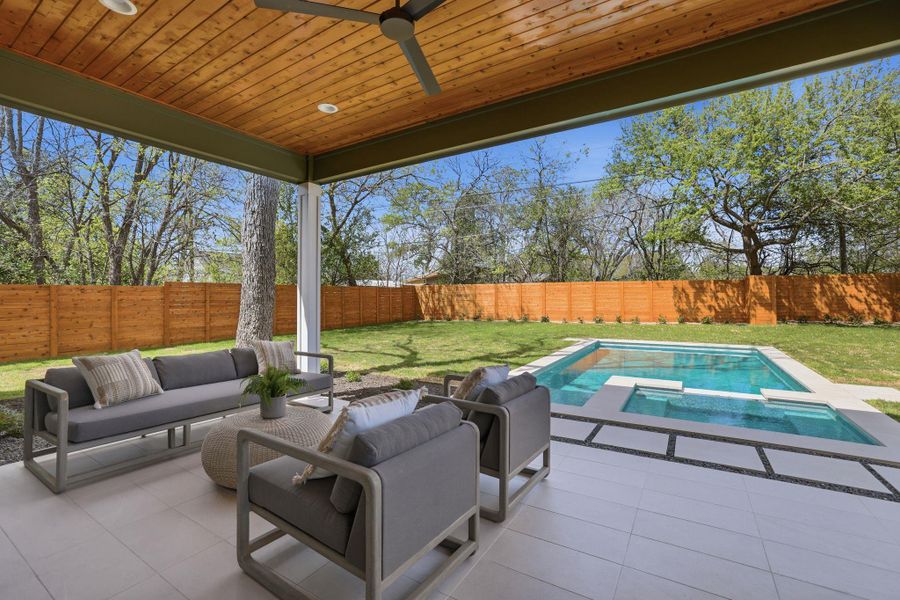 Fenced backyard with outdoor lounge area, a pool with connected hot tub, a patio area, and ceiling fan