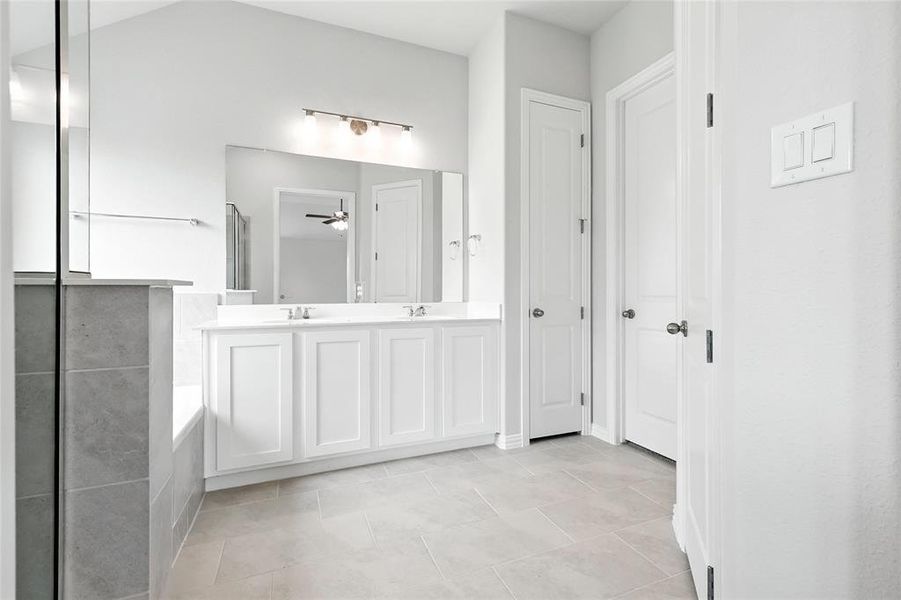 Full bathroom featuring double vanity, a tub to relax in, a closet, and tile patterned floors Full bathroom featuring double vanity, a tub to relax in, a closet, and tile patterned floors