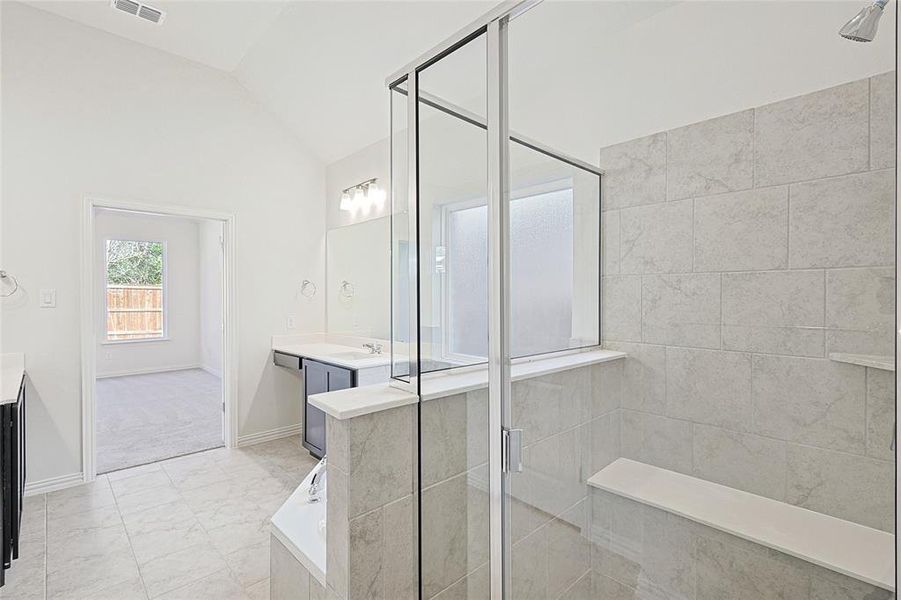 Bathroom featuring vanity, plus walk in shower, and lofted ceiling