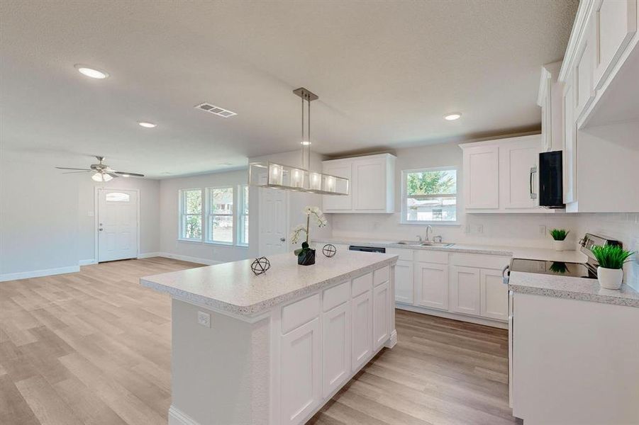 Kitchen featuring white cabinetry, a center island, and a wealth of natural light