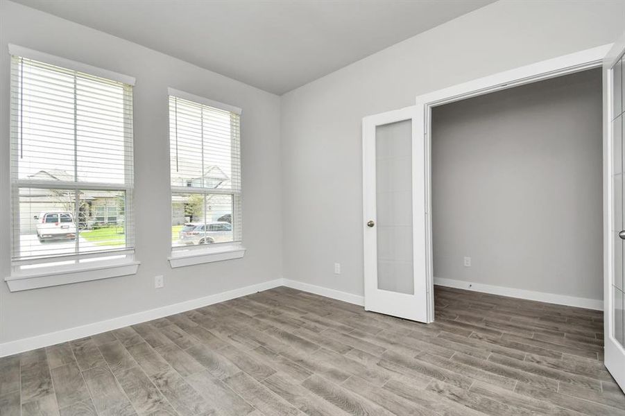 Quietly nestled in front of the home is the sophisticated home office. Featuring plush carpet, custom paint tones, and large windows with privacy blinds. Sample photo of completed home with similar floor plan. As-built interior colors and selections may vary.