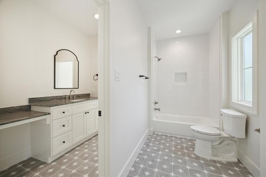 Star-patterned tile flooring adds a bold, playful touch, while the white subway-tiled shower with a built-in niche provides timeless elegance. Matte black fixtures and a unique arched mirror bring a modern flair, creating a bathroom that balances aesthetics with practicality.