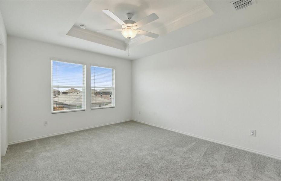 Oversized Owner's suite with large windows and elegant tray ceiling *real home pictured