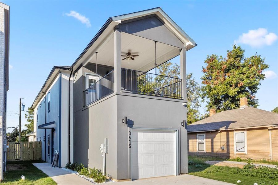 View of front of home with ceiling fan, a balcony, and a garage