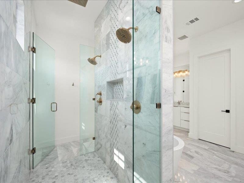 Bathroom with a marble finish shower, a freestanding bath, and vanity