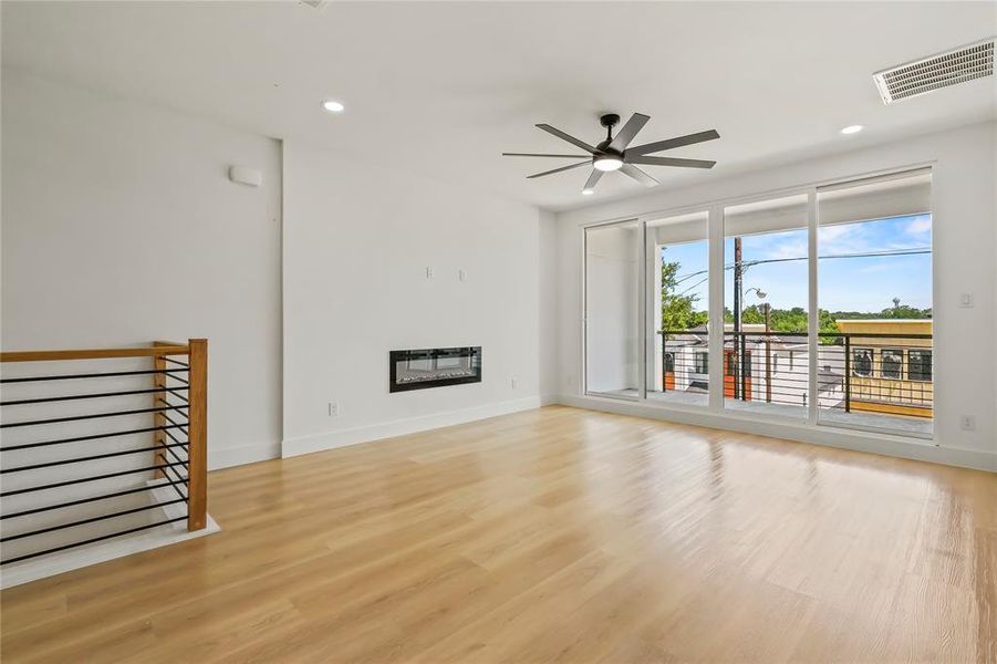 Unfurnished living room featuring a glass covered fireplace, recessed lighting, light wood-type flooring, and a ceiling fan