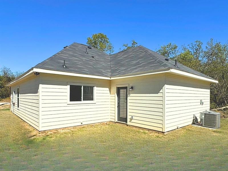 Rear view of property with a yard and a shingled roof