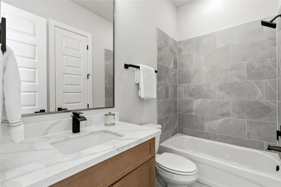 A well-appointed secondary bathroom featuring a quartz vanity and full tub and shower combination. A well-appointed secondary bathroom featuring a quartz vanity and full tub and shower combination.
