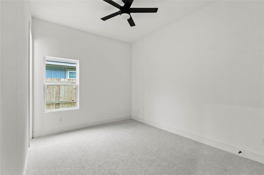 Carpeted empty room with baseboards and a ceiling fan