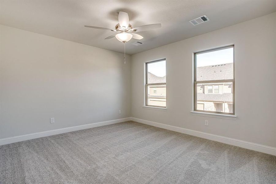 Empty room featuring light colored carpet and a ceiling fan