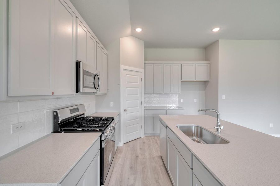 A well-lit kitchen presents a functional island with an undermount sink, complemented by sleek cabinetry and modern appliances. A well-lit kitchen presents a functional island with an undermount sink, complemented by sleek cabinetry and modern appliances.