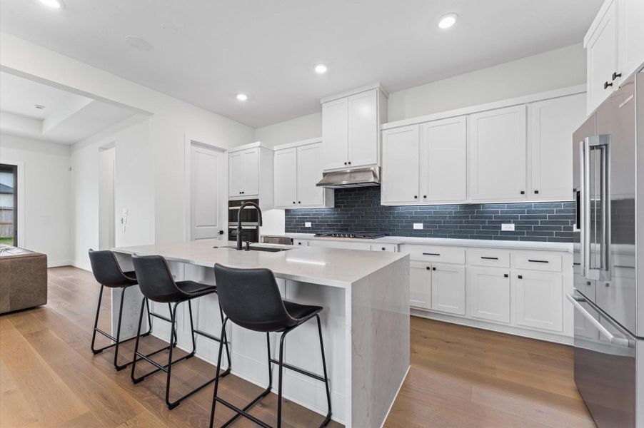 The island anchors the kitchen with comfortable seating — a natural spot for morning coffee, casual meals, or conversation while dinner's on.