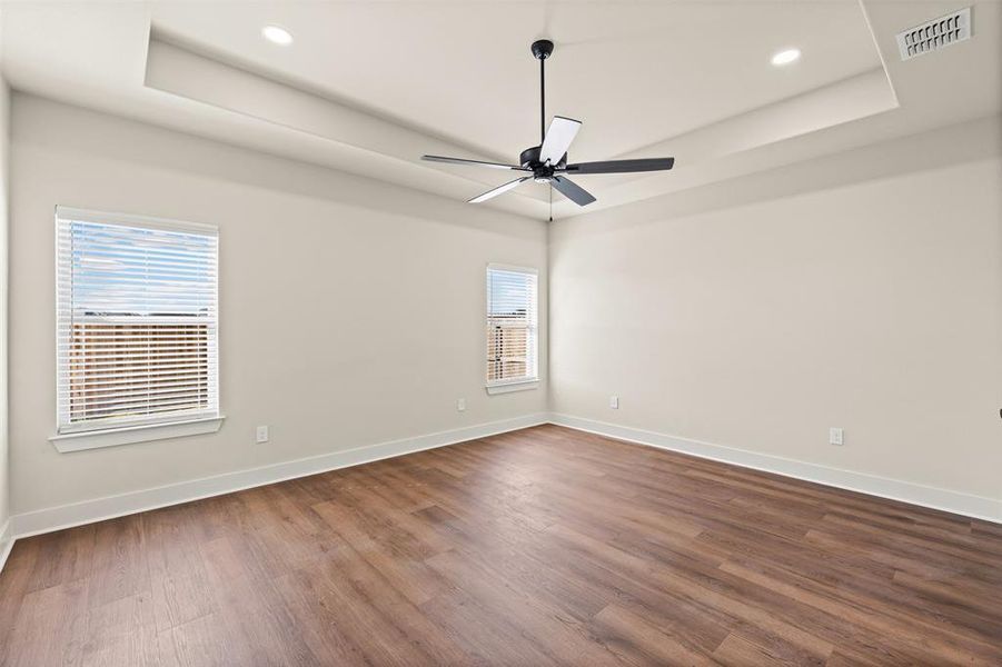 Unfurnished room featuring a raised ceiling, dark wood-style floors, recessed lighting, and ceiling fan
