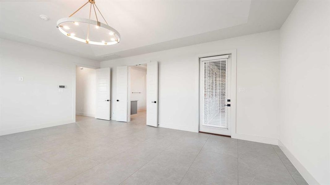 Empty room featuring light tile patterned flooring and an inviting chandelier