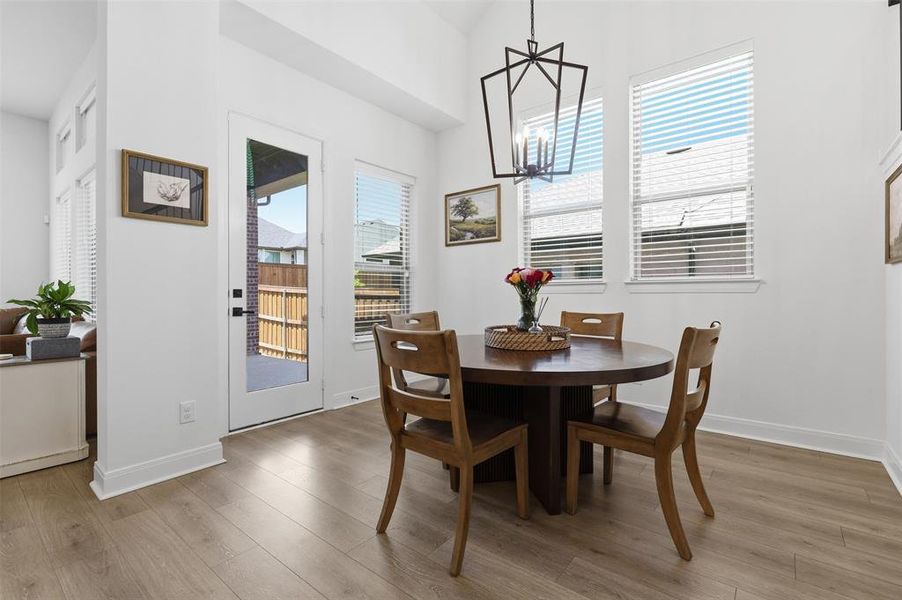 Dining area featuring wood-finish flooring, white walls, and a contemporary black chandelier Dining area featuring wood-finish flooring, white walls, and a contemporary black chandelier