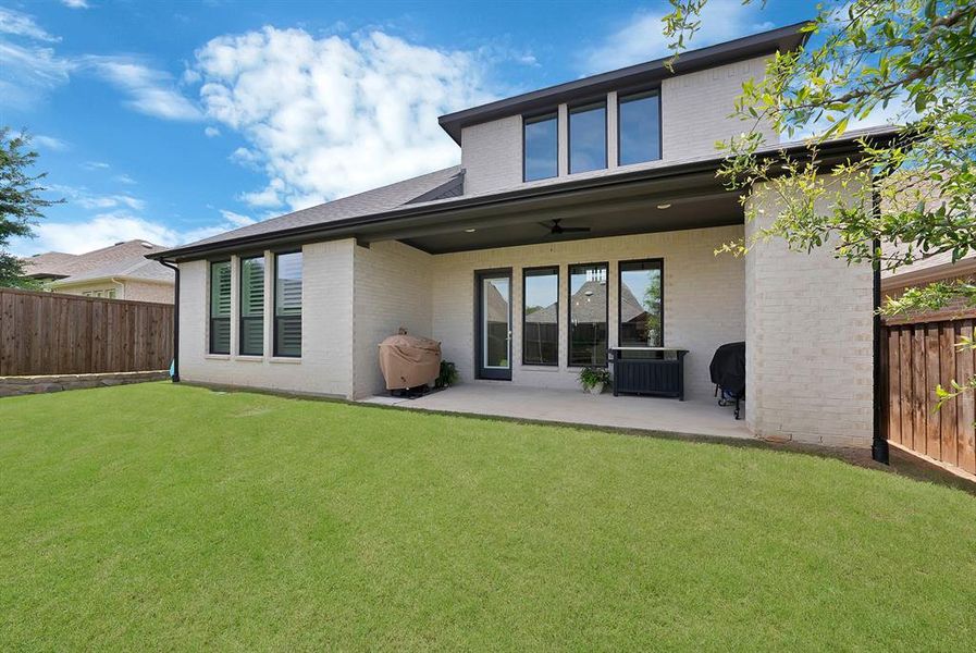 Expansive backyard featuring a manicured lawn, a large concrete patio, and a covered outdoor living area Expansive backyard featuring a manicured lawn, a large concrete patio, and a covered outdoor living area
