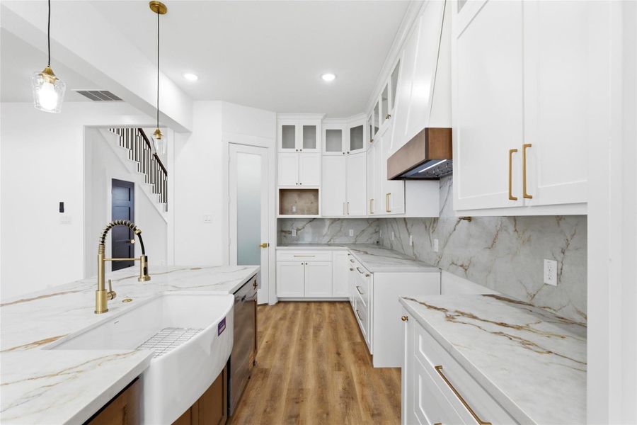 A stunning kitchen with custom solid wood cabinetry, thoughtfully designed with dedicated storage for a built-in microwave, spice rack, utensil holder, trash bin, and more.