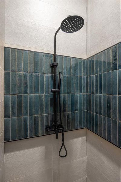 Bathroom view of a walk in shower and a textured wall