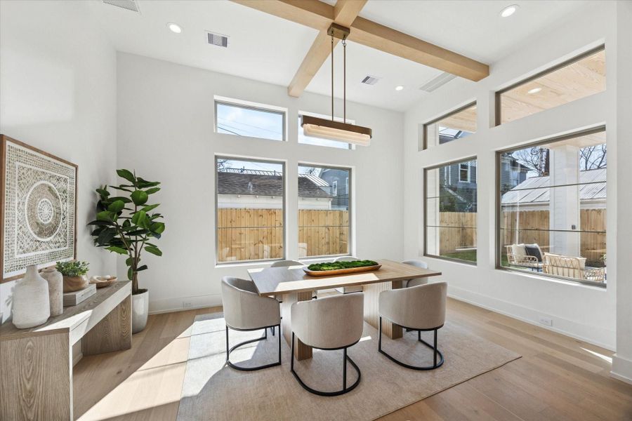Spacious breakfast room (or dining room) adjacent to the kitchen, overlooking the backyard and anchored by a striking light fixture and wood beams.